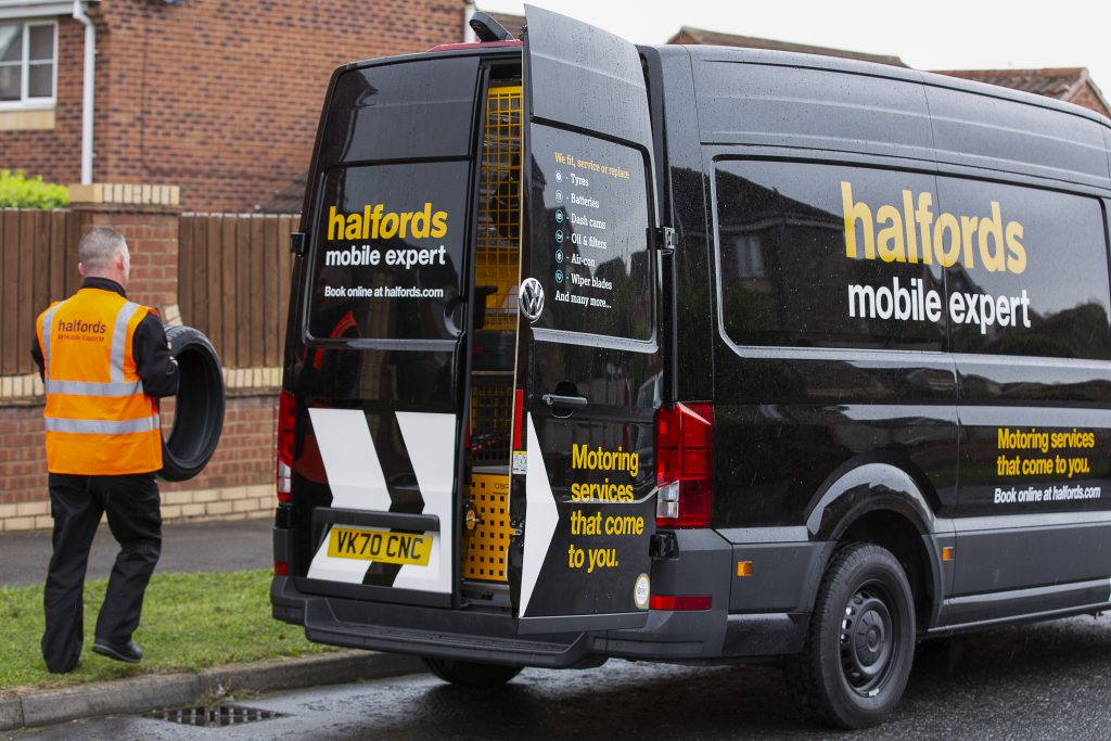 Halfords mobile expert van parked on street with technician carrying a tyre